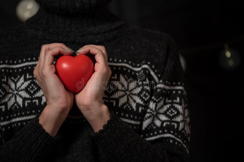 La ragazza in un maglione scuro dell'inverno tiene il grande cuore rosso a disposizione fotografia stock libera da diritti La ragazza in un maglione scuro dell'inverno tiene il grande cuore rosso a disposizione fotografia stock libera da diritti
