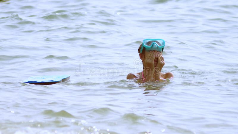 La ragazza in una maschera subacquea nuota sotto l'acqua, gli sguardi al mondo subacqueo ed il piccolo pesce tropicale