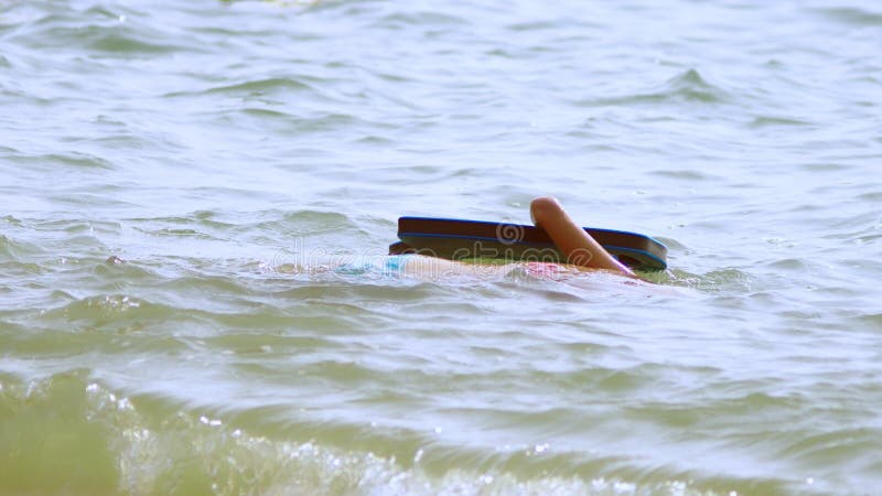 La ragazza in una maschera subacquea nuota sotto l'acqua, gli sguardi al mondo subacqueo ed il piccolo pesce tropicale