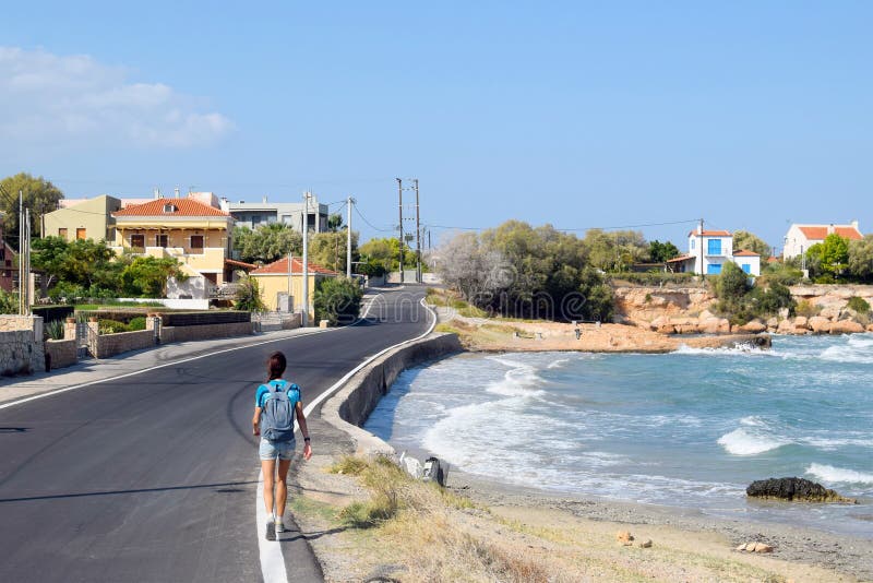La ragazza va lungo la strada vicino alla costa di mare, la spiaggia del mar Mediterraneo sull'isola fotografie stock libere da diritti La ragazza va lungo la strada vicino alla costa di mare, la spiaggia del mar Mediterraneo sull'isola fotografie stock libere da diritti