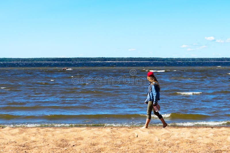 La ragazza va a piedi nudi dal mare fotografia stock La ragazza va a piedi nudi dal mare fotografia stock