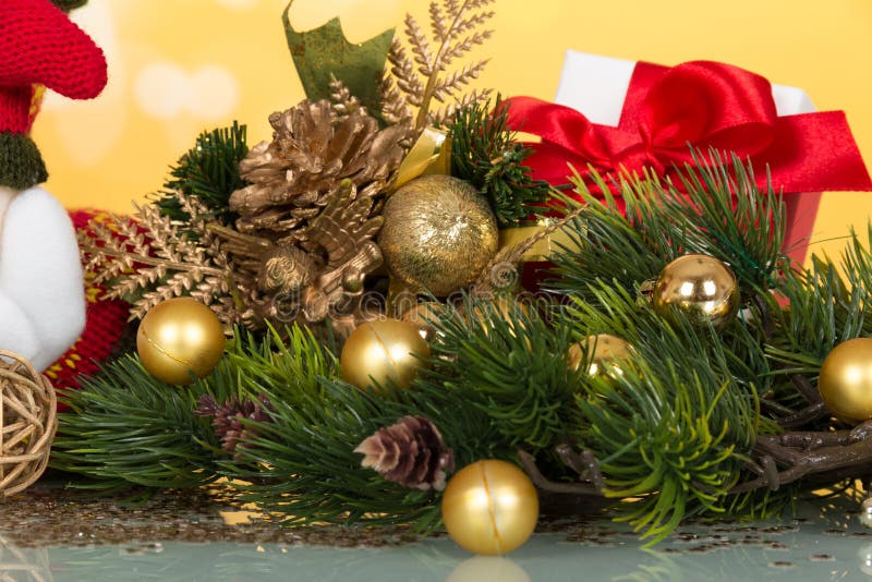 La rama del pino embelleció bolas de la Navidad, la figurilla del recuerdo, y la caja de oro con el regalo en amarillo fotografía de archivo La rama del pino embelleció bolas de la Navidad, la figurilla del recuerdo, y la caja de oro con el regalo en amarillo fotografía de archivo