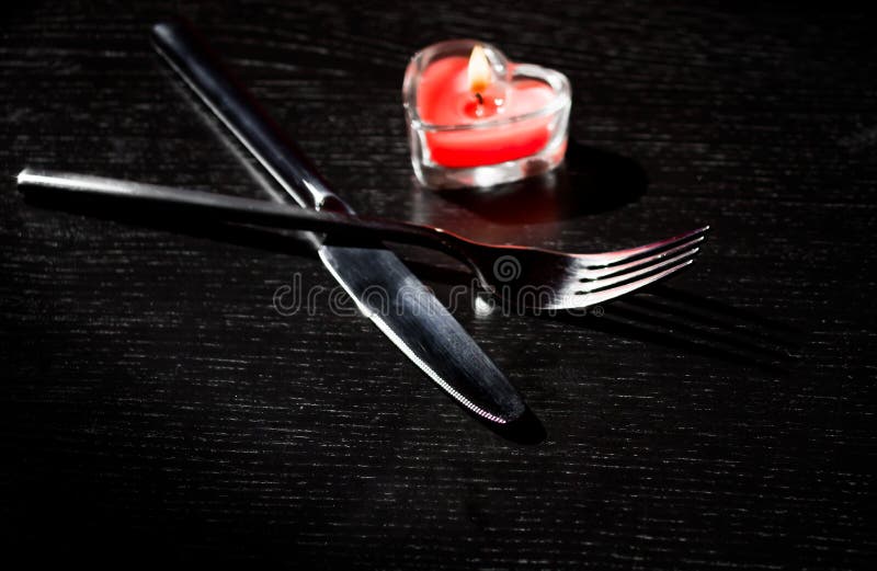 La regolazione della tavola di giorno di S. Valentino con il coltello, forcella, cuore bruciante rosso ha modellato la candela immagine stock libera da diritti La regolazione della tavola di giorno di S. Valentino con il coltello, forcella, cuore bruciante rosso ha modellato la candela immagine stock libera da diritti