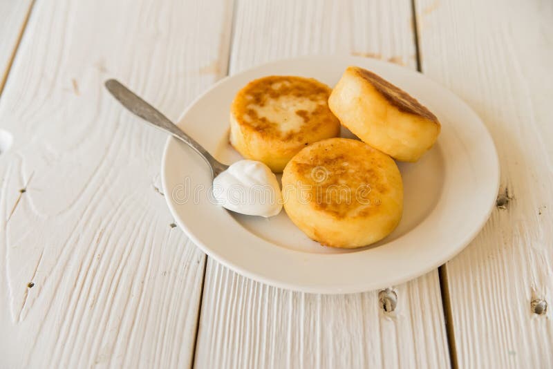 La ricotta agglutina sul piatto con panna acida immagini stock libere da diritti La ricotta agglutina sul piatto con panna acida immagini stock libere da diritti
