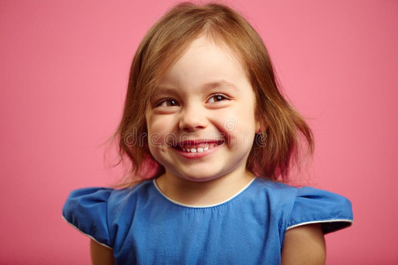 La risata sveglia del bambino femminile, ha confuso il fronte, spalle timido scrollate le spalle immagine stock La risata sveglia del bambino femminile, ha confuso il fronte, spalle timido scrollate le spalle immagine stock