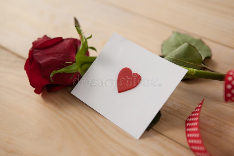 La rose de rouge enveloppée au ruban et au coeur a imprimé l'enveloppe photos stock
