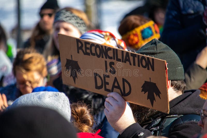 OTTAWA, ONTARIO, CANADA - FEBRUARY 17, 2019: A sign reads `Reconciliation is Dead` and depicts inverted maple leaves at a protest of RCMP intervention in BC`s indigenous Wet`suwet`en First Nation lands. OTTAWA, ONTARIO, CANADA - FEBRUARY 17, 2019: A sign reads `Reconciliation is Dead` and depicts inverted maple leaves at a protest of RCMP intervention in BC`s indigenous Wet`suwet`en First Nation lands.