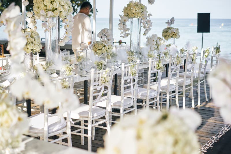 La sede di nozze per la tavola di cena di ricezione decorata con le orchidee bianche, rose bianche, fiori, sedie floreali e bianc