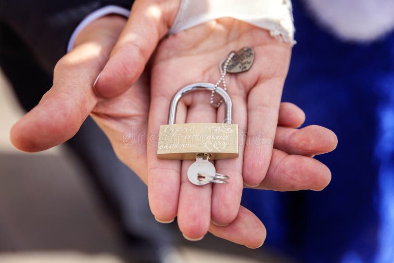 La serratura in mani delle persone appena sposate immagini stock libere da diritti La serratura in mani delle persone appena sposate immagini stock libere da diritti