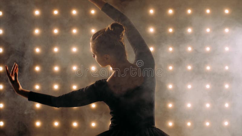 La silhouette de la ballerine dans la robe noire danse du ballet dans le studio sombre