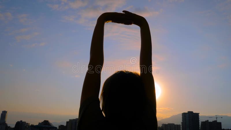 La silhouette de la femme s'étire les bras contre le ciel du lever du soleil banque de vidéos