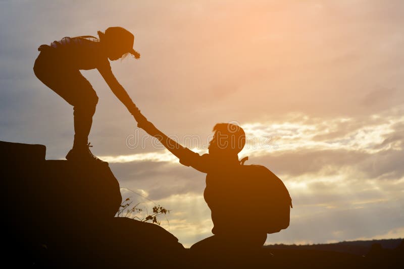 La silhouette de la fille aide un garçon sur la montagne photo stock La silhouette de la fille aide un garçon sur la montagne photo stock