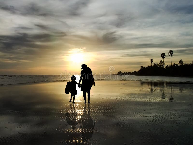 La silueta de la familia que mira la salida del sol en la playa fotografía de archivo libre de regalías La silueta de la familia que mira la salida del sol en la playa fotografía de archivo libre de regalías