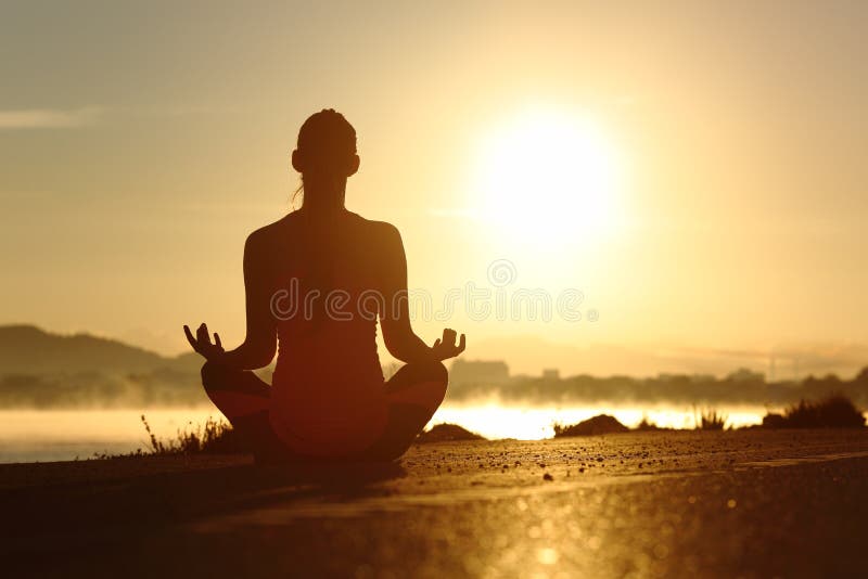 La silueta de una mujer de la aptitud que ejercita la meditación de la yoga ejercita