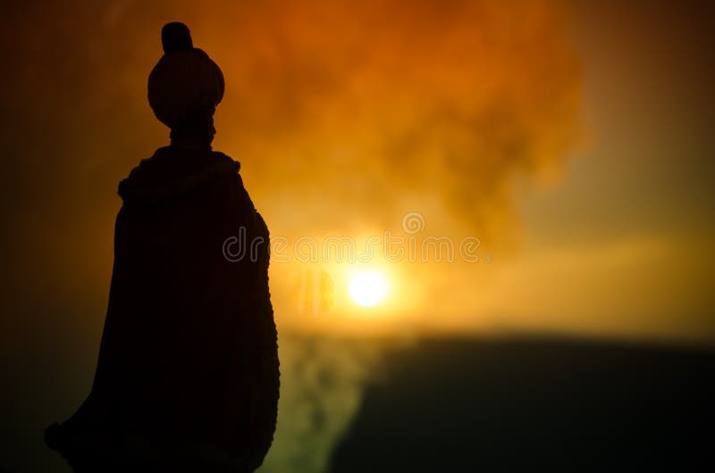 La siluetta dell'uomo arabo sta da solo nel deserto e nella sorveglianza del tramonto con le nuvole di nebbia Favola orientale fotografia stock libera da diritti La siluetta dell'uomo arabo sta da solo nel deserto e nella sorveglianza del tramonto con le nuvole di nebbia Favola orientale fotografia stock libera da diritti