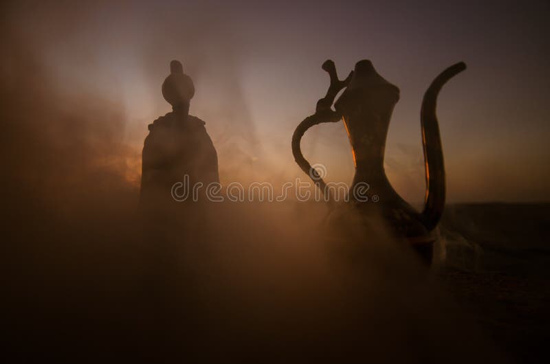 La siluetta dell'uomo arabo sta da solo nel deserto e nella sorveglianza del tramonto con le nuvole di nebbia Favola orientale fotografie stock libere da diritti La siluetta dell'uomo arabo sta da solo nel deserto e nella sorveglianza del tramonto con le nuvole di nebbia Favola orientale fotografie stock libere da diritti