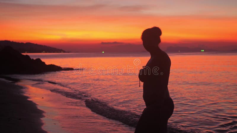 La siluetta della giovane donna in bikini gode di di camminare sulla spiaggia al tramonto adorabile Movimento lento 3840x2160