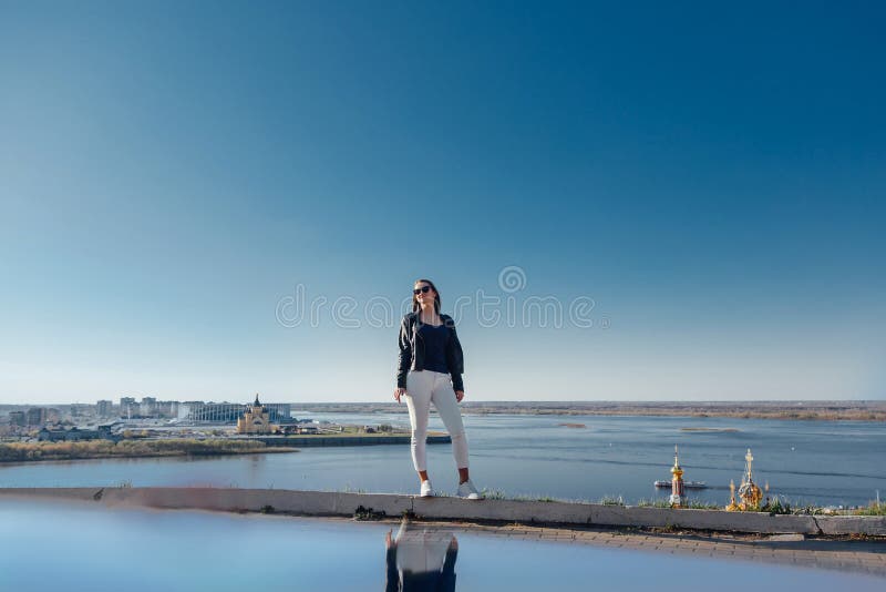 La situaci?n elegante de la muchacha en una monta?a, cielo azul reflej? en el agua foto de archivo La situaci?n elegante de la muchacha en una monta?a, cielo azul reflej? en el agua foto de archivo