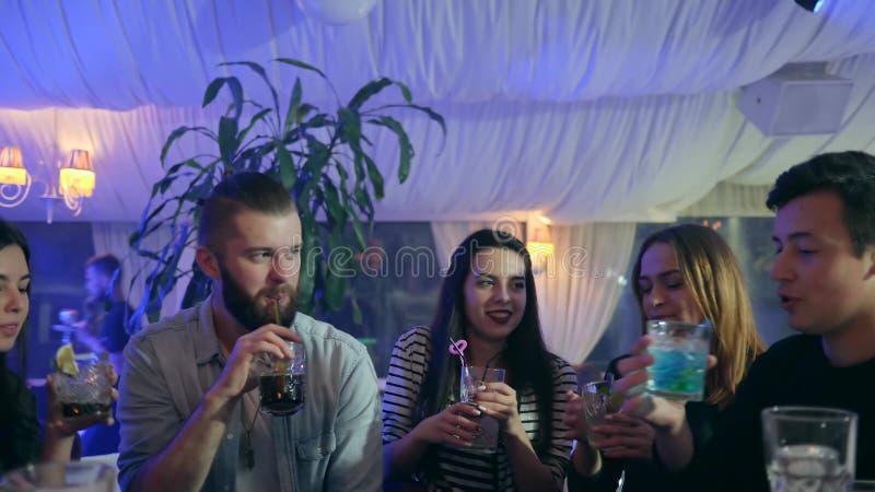 La société gaie des amis font le pain grillé avec des verres dans des mains la nuit faire la fête