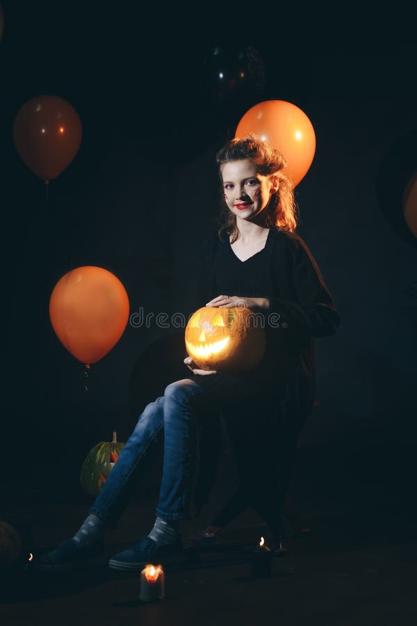 La sorcière de Halloween avec un potiron et une magie découpés s'allume dans une femme étonnée par jeunes foncés de forêt de beau image libre de droits La sorcière de Halloween avec un potiron et une magie découpés s'allume dans une femme étonnée par jeunes foncés de forêt de beau image libre de droits