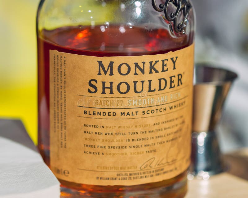 La spalla della scimmia ha mescolato il primo piano della bottiglia di Malt Whisky a Kiev, Ucraina