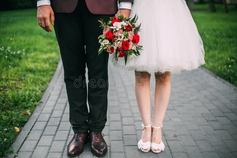 La sposa e lo sposo senza volto sono in piedi per strada e tengono la mano, tenendo un bouquet nuziale brillante fotografia stock libera da diritti La sposa e lo sposo senza volto sono in piedi per strada e tengono la mano, tenendo un bouquet nuziale brillante fotografia stock libera da diritti