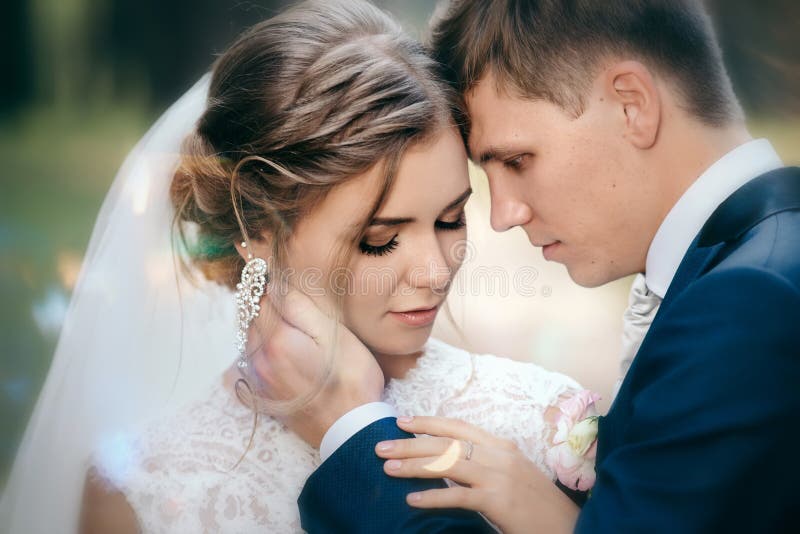 La sposa e lo sposo in vestiti da sposa su sfondo naturale La giovane coppia sbalorditiva è incredibilmente felice Giorno delle n fotografia stock La sposa e lo sposo in vestiti da sposa su sfondo naturale La giovane coppia sbalorditiva è incredibilmente felice Giorno delle n fotografia stock