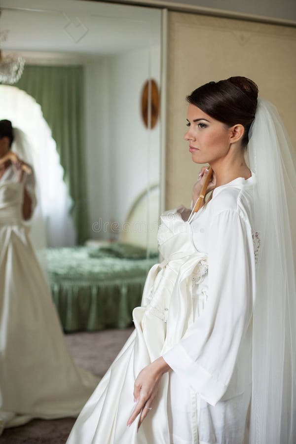 Bride removes wedding dress with hanger for fitting. Bride removes wedding dress with hanger for fitting