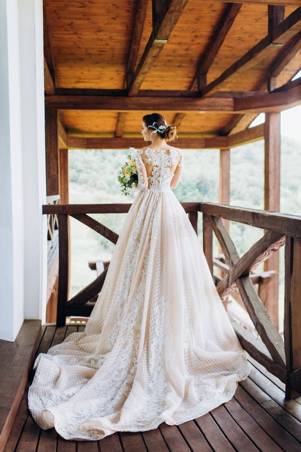 La sposa in un magnifico, bianco, vestito da sposa con un treno lungo fotografia stock La sposa in un magnifico, bianco, vestito da sposa con un treno lungo fotografia stock