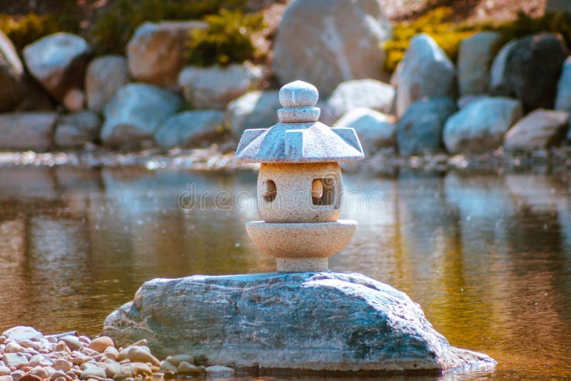 La statue de lanterne japonaise se tient seule sur une péninsule dans les jardins japonais photos libres de droits La statue de lanterne japonaise se tient seule sur une péninsule dans les jardins japonais photos libres de droits