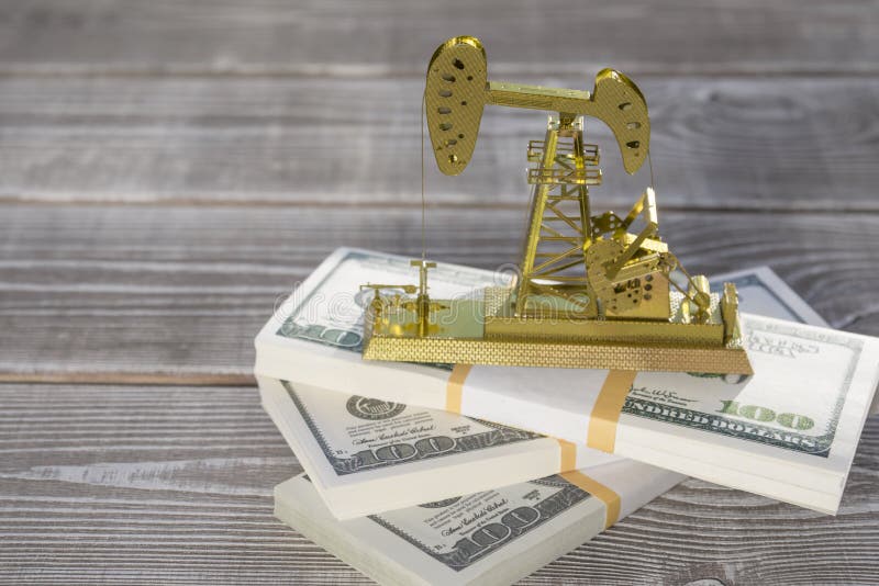 La stazione d'oscillazione della perforazione della pompa di olio sta sui pacchi delle banconote del dollaro immagini stock La stazione d'oscillazione della perforazione della pompa di olio sta sui pacchi delle banconote del dollaro immagini stock