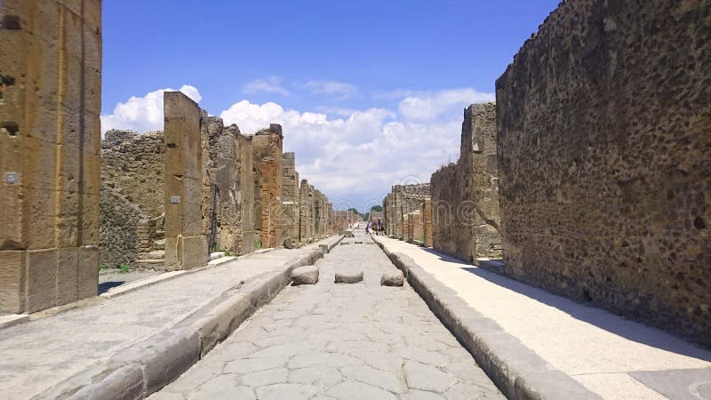 La strada antica lunga a Pompei ha fiancheggiato dalle vecchie pareti che scompaiono al punto di sparizione nella distanza con l' fotografie stock libere da diritti La strada antica lunga a Pompei ha fiancheggiato dalle vecchie pareti che scompaiono al punto di sparizione nella distanza con l' fotografie stock libere da diritti