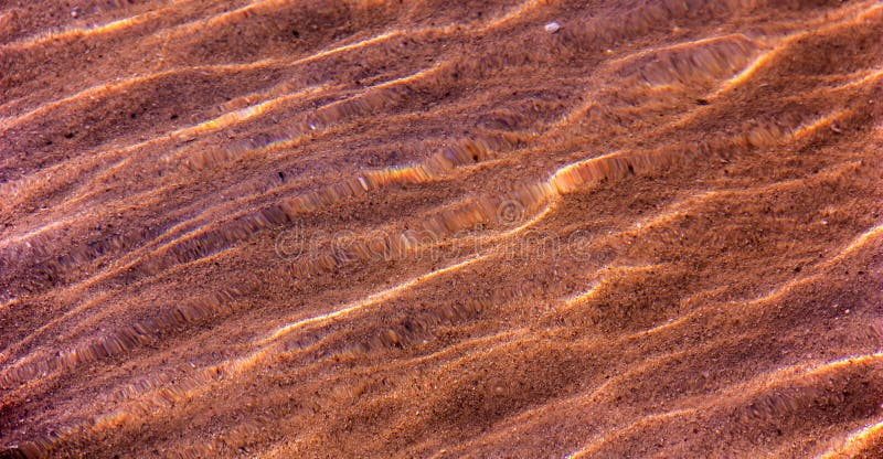 La struttura della sabbia sul fondo attraverso l'acqua immagine stock La struttura della sabbia sul fondo attraverso l'acqua immagine stock