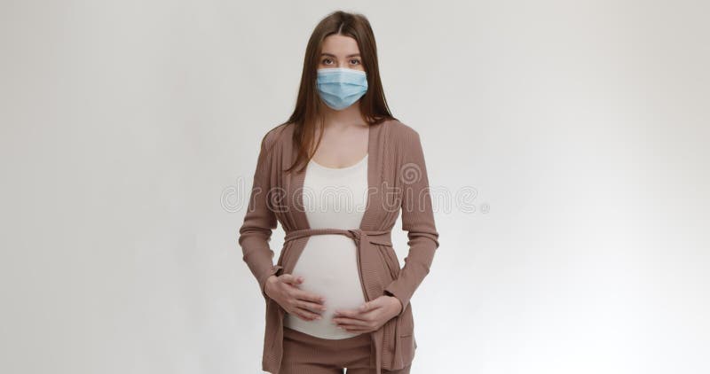 La sûreté et la sécurité personnelles. Jeune femme enceinte portant le masque protecteur medical frottant son gros ventre clips vidéos