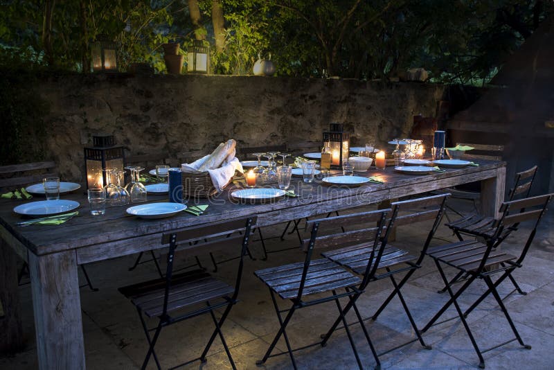 La tabla rústica grande se preparó para una cena exterior en la noche