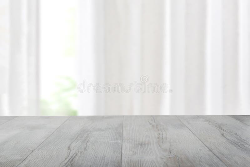 La table lumineuse en bois rustique vide devant le fond vert naturel floue de fenêtre de rideau. Modèle pour votre produit