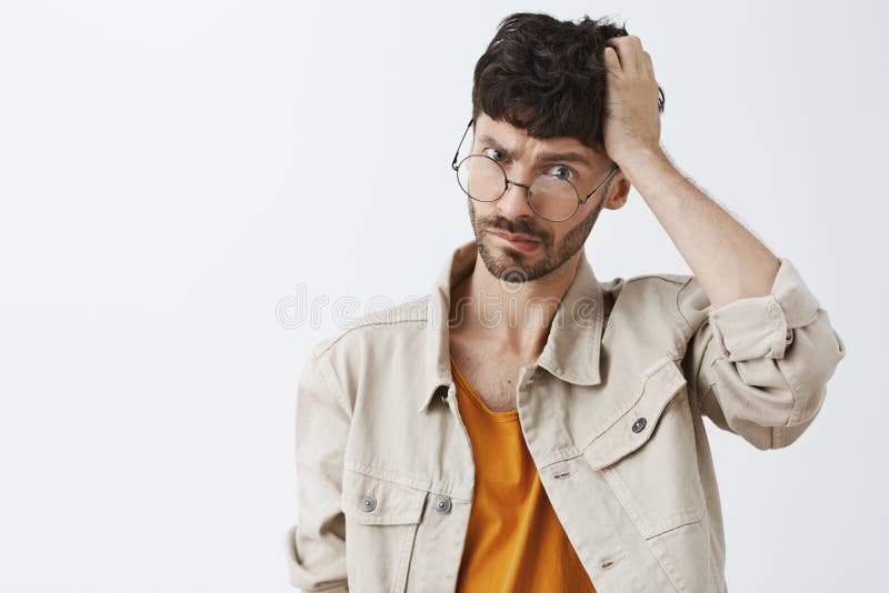 La taille- a tiré du jeune homme beau confus avec la barbe et l'éraflure élégante foncée de coiffure principales et le froncement photos libres de droits La taille- a tiré du jeune homme beau confus avec la barbe et l'éraflure élégante foncée de coiffure principales et le froncement photos libres de droits
