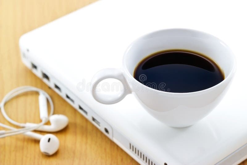 La tasse de café sur l'ordinateur portable et l'écouteur blancs, détendent le temps et les affaires image stock La tasse de café sur l'ordinateur portable et l'écouteur blancs, détendent le temps et les affaires image stock