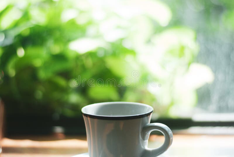 La taza de café de cerámica blanca de la placa se coloca sobre la mesa de madera de la cafetería