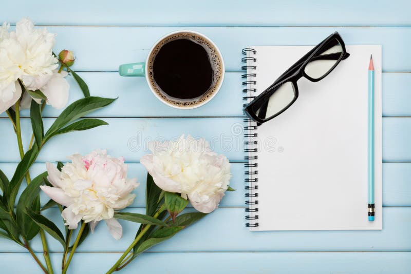 La taza de café de la mañana, el cuaderno vacío, el lápiz, los vidrios y la peonía blanca florece en la tabla de madera azul, des imágenes de archivo libres de regalías La taza de café de la mañana, el cuaderno vacío, el lápiz, los vidrios y la peonía blanca florece en la tabla de madera azul, des imágenes de archivo libres de regalías