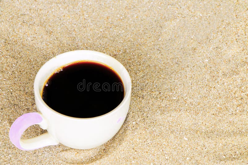 La taza de café puso en arena en la playa foto de archivo La taza de café puso en arena en la playa foto de archivo