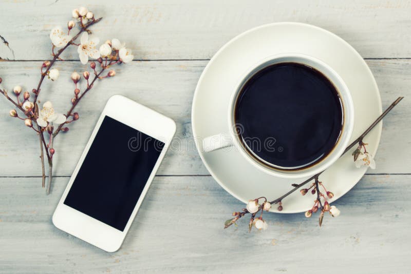 La taza de café sólo y de smartphone, en la tabla de madera con la cereza florece, visión superior, filtro del vintage imagenes de archivo La taza de café sólo y de smartphone, en la tabla de madera con la cereza florece, visión superior, filtro del vintage imagenes de archivo