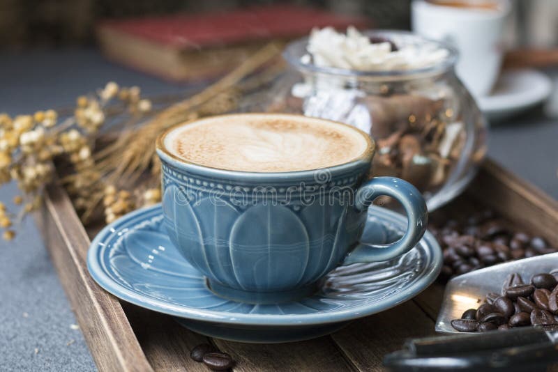 La taza del Latte, el grano de café, el libro y las flores secadas sacuden en de madera fotos de archivo libres de regalías La taza del Latte, el grano de café, el libro y las flores secadas sacuden en de madera fotos de archivo libres de regalías
