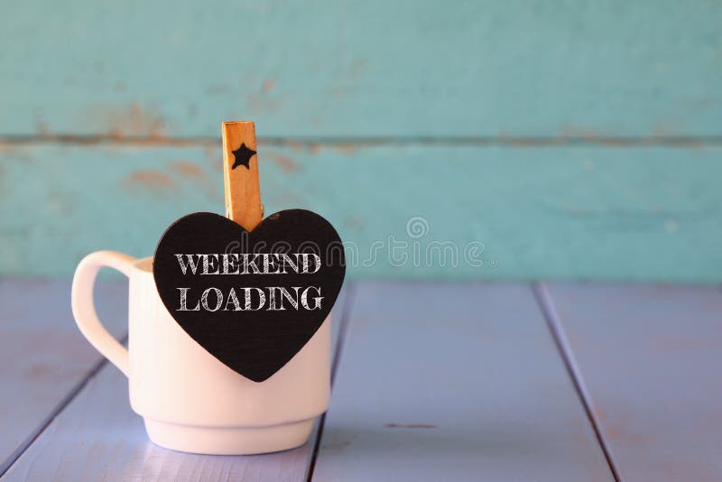 Cup of coffee and little heart shape chalkboard with the phrase: WEEKEND LOADING. Cup of coffee and little heart shape chalkboard with the phrase: WEEKEND LOADING