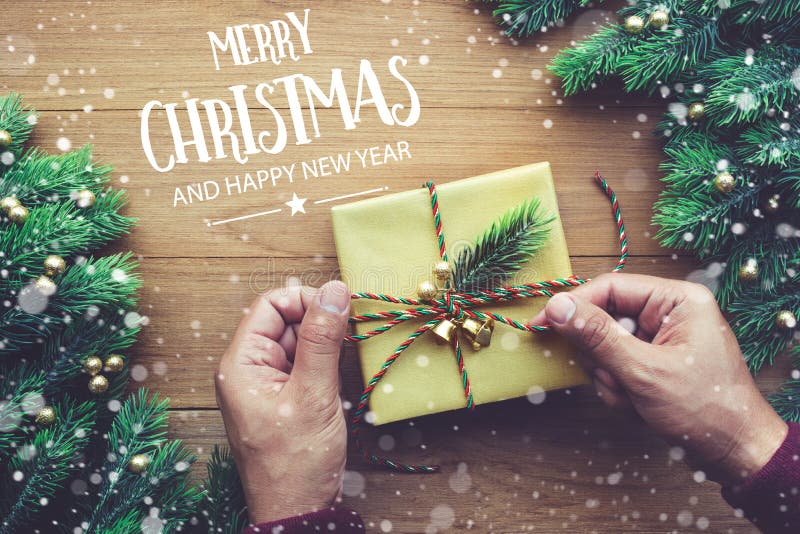 La tipografía de la FELIZ NAVIDAD Y de la FELIZ AÑO NUEVO, texto con la mano humana que adorna la caja de regalo presenta imagen de archivo libre de regalías La tipografía de la FELIZ NAVIDAD Y de la FELIZ AÑO NUEVO, texto con la mano humana que adorna la caja de regalo presenta imagen de archivo libre de regalías