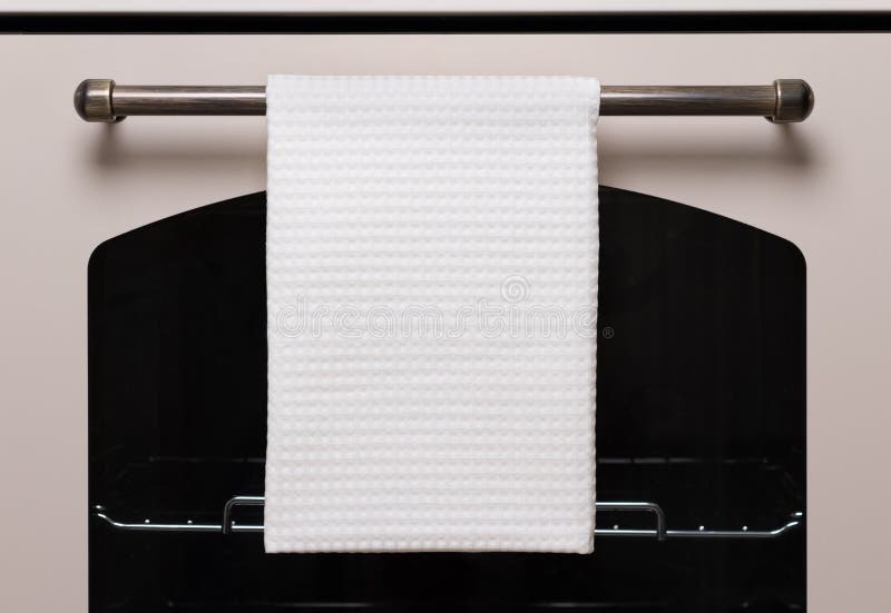 La toalla de cocina blanca cuelga en la manija del horno, maqueta del producto