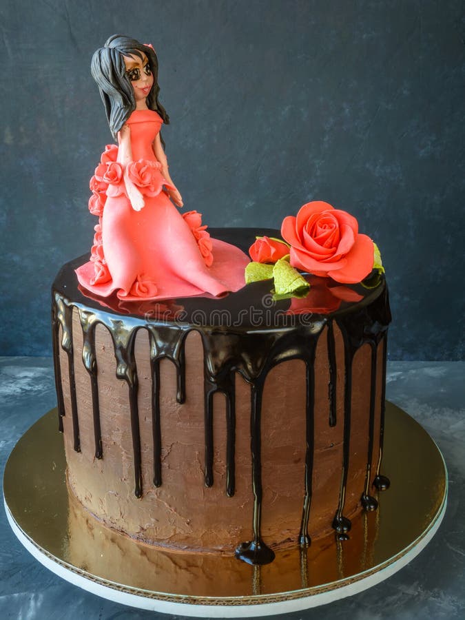 La torta hecha a mano cubrió un esmalte negro del chocolate con la figura de una muchacha en un vestido rojo y una rosa roja en u fotografía de archivo libre de regalías La torta hecha a mano cubrió un esmalte negro del chocolate con la figura de una muchacha en un vestido rojo y una rosa roja en u fotografía de archivo libre de regalías
