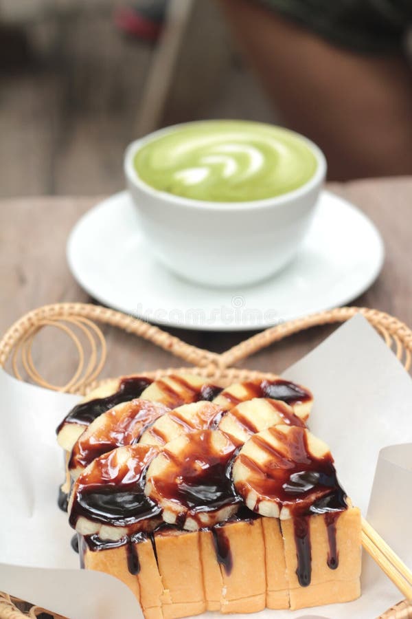La tostada remató con los plátanos y el chocolate - té con leche verde imagen de archivo libre de regalías La tostada remató con los plátanos y el chocolate - té con leche verde imagen de archivo libre de regalías