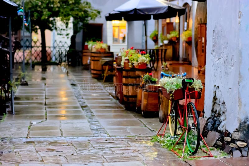 La tranquilidad y el café abandonado acogedor de la calle en el otoño llueven Bicicleta vieja adornada con las flores imagen de archivo libre de regalías La tranquilidad y el café abandonado acogedor de la calle en el otoño llueven Bicicleta vieja adornada con las flores imagen de archivo libre de regalías