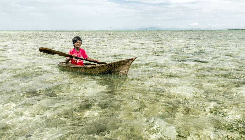 La tribù di Bajau scherza divertiresi remando la piccola barca vicino alle loro case del villaggio in mare, Sabah Semporna, Males immagine stock La tribù di Bajau scherza divertiresi remando la piccola barca vicino alle loro case del villaggio in mare, Sabah Semporna, Males immagine stock